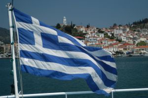 greece flag overlooking small town