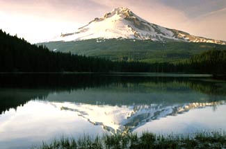 Oregon, Mount Hood. Image is of the mountain in the background with water in front and tress on both sides. Image is in full colour. 
